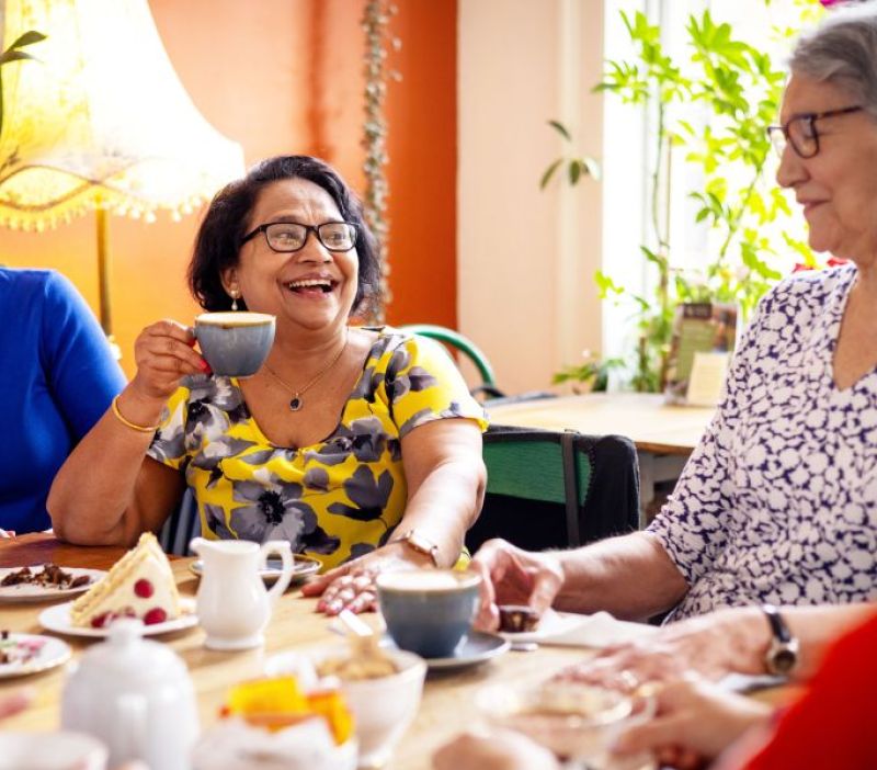 people sitting around a table enjoying a cup of tea and cake